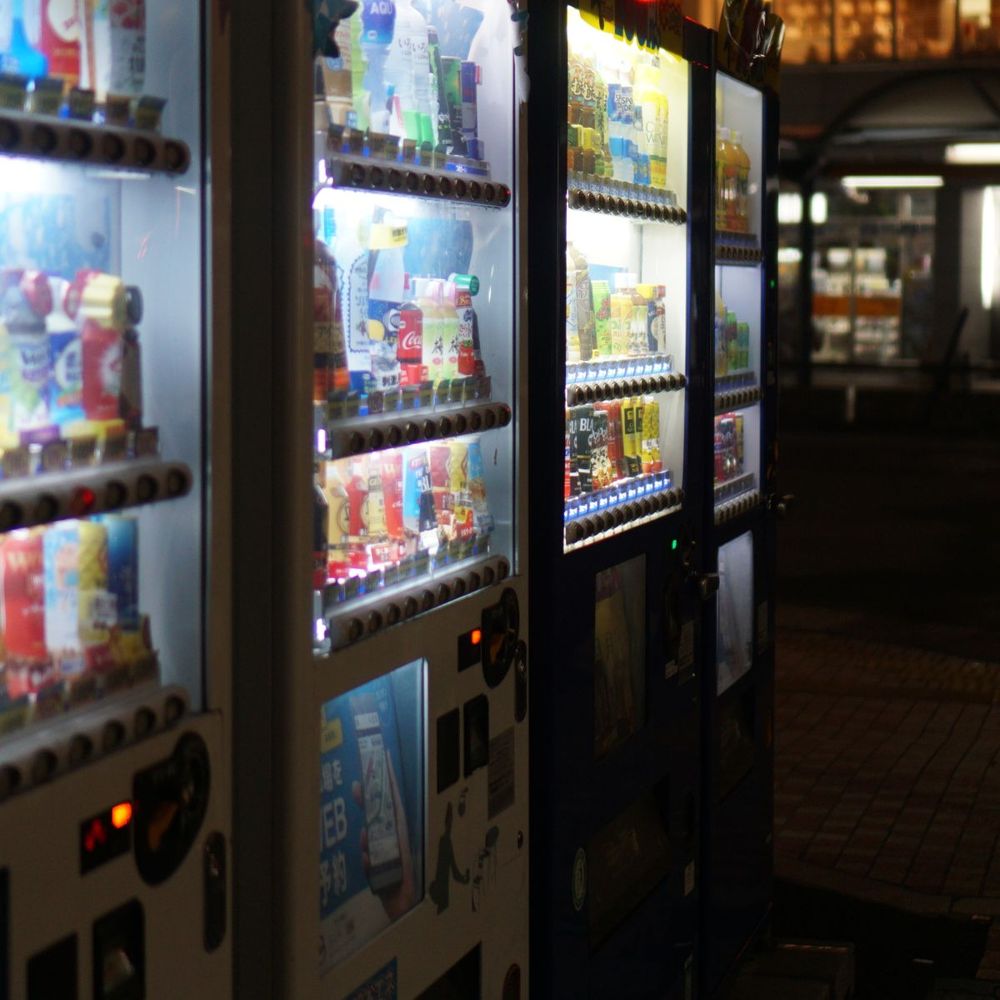 Lit vending machines stocked with drinks and snacks
